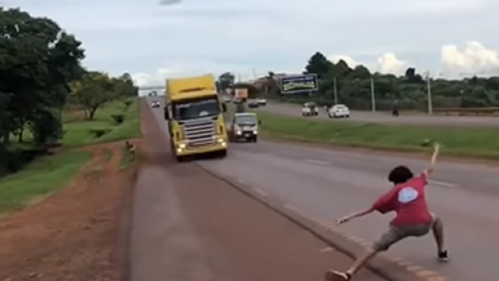 Un joven es grabado por un amigo mientras realiza se pone en frente a un camión que circula a alta velocidad en Minga Guazú.Foto: Captura de video Telefuturo.