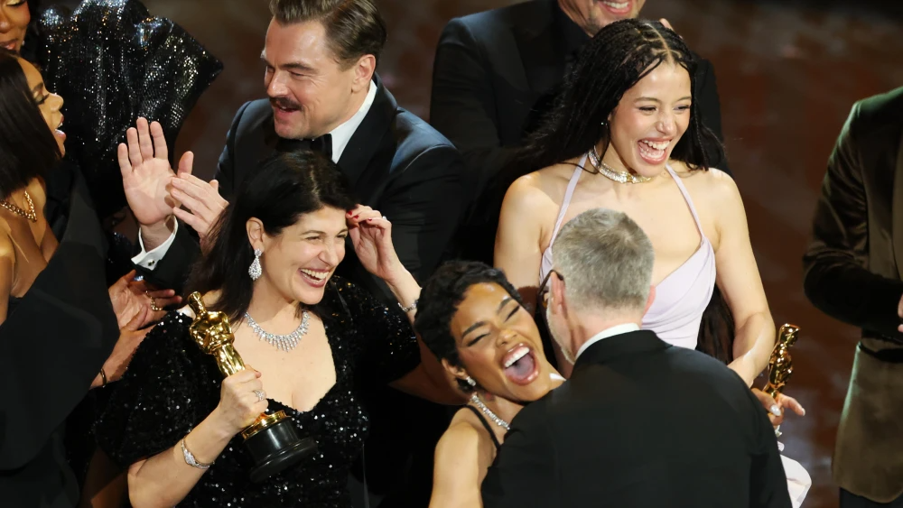 Leonardo DiCaprio (en el centro a la izquierda), Chase Infiniti (en el centro a la derecha), Paul Thomas Anderson (a la derecha) se abrazan mientras la productora Sara Murphy (a la izquierda) y Teyana Taylor (en primer plano en el centro) celebran tras ganar el Óscar a la mejor película por Una batalla tras otra.Foto: Chris Torres/EFE.